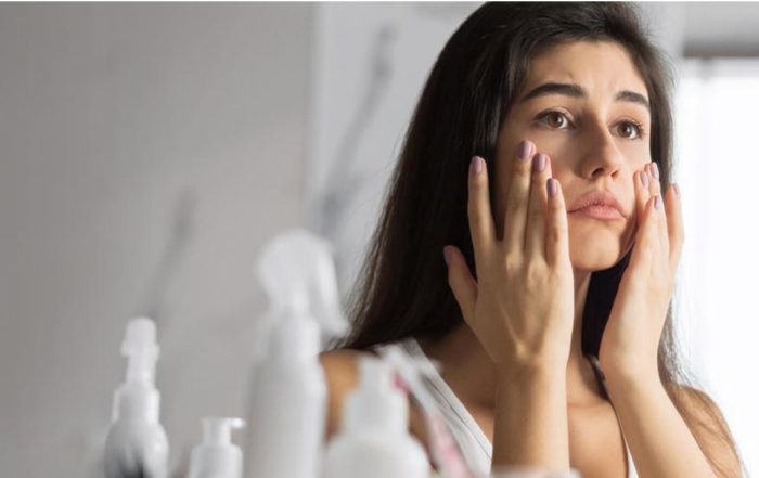 Woman looking at her skin showing signs of stress